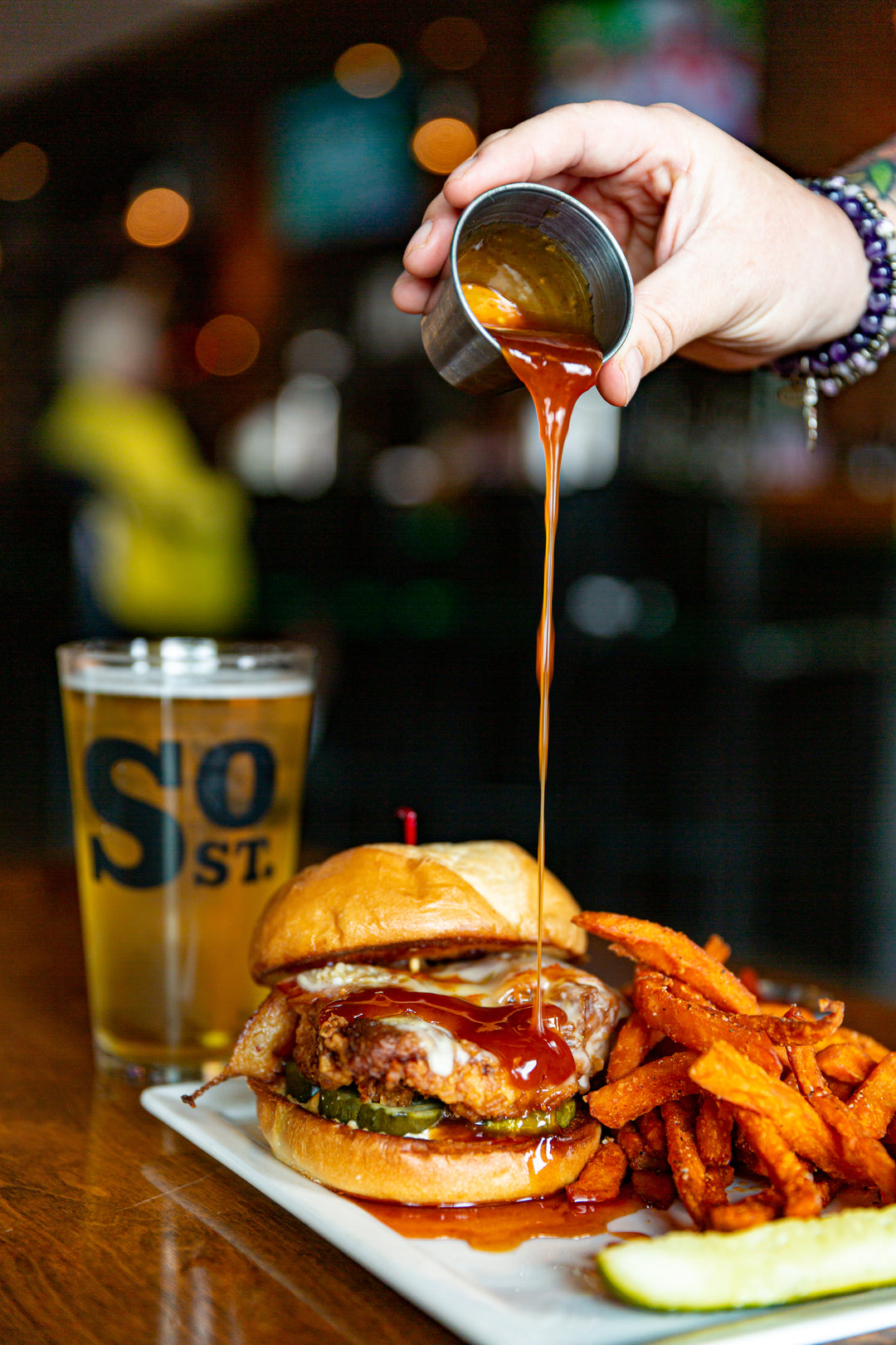 South Street Chicken Sandwich with hot honey being poured on it.