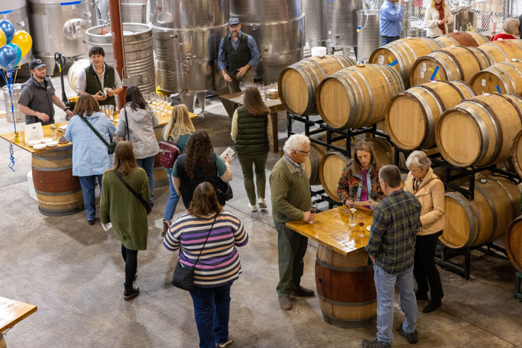 People visiting a brewery with barrels and staff in the background