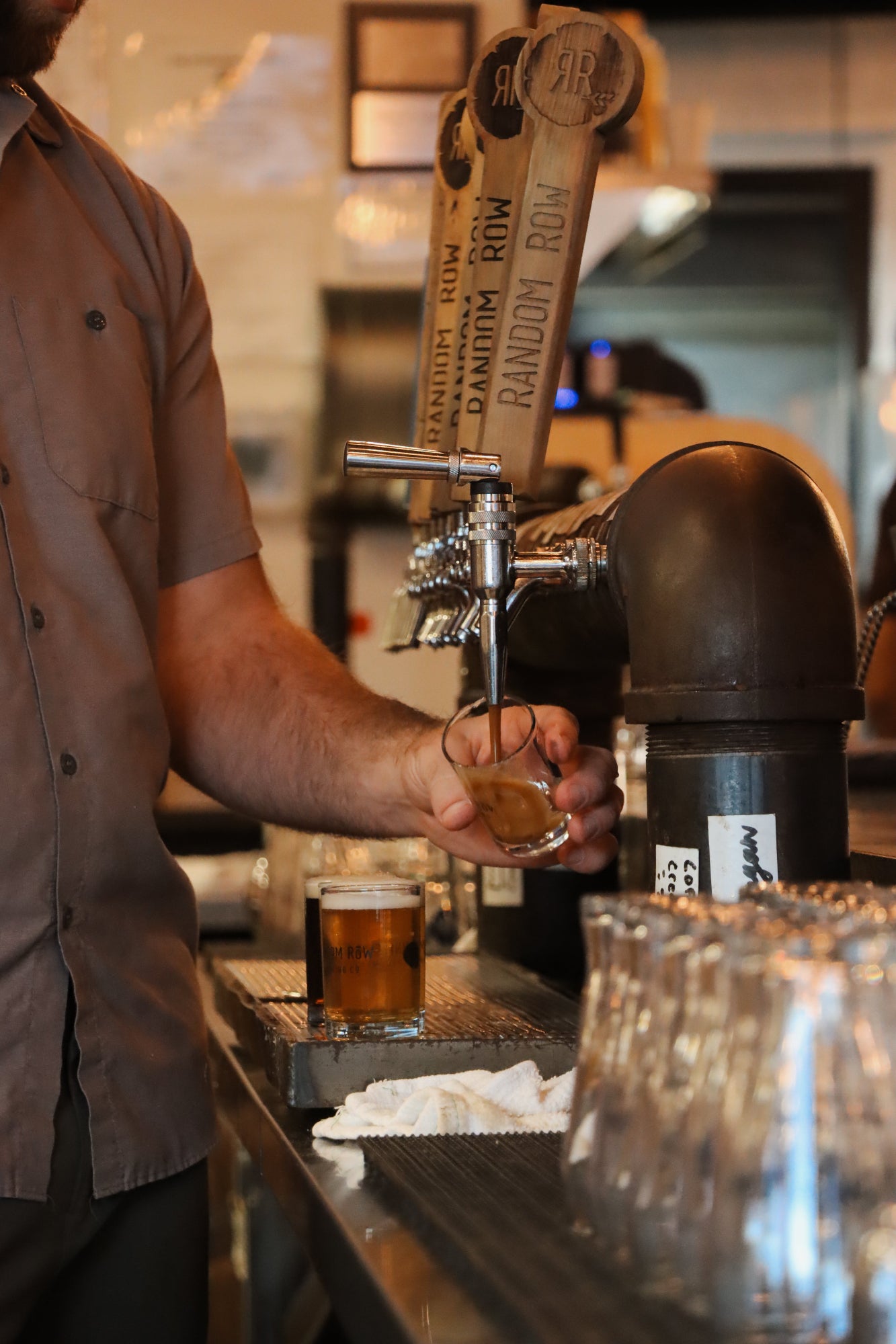 Person pouring a beer from a tap at a bar.