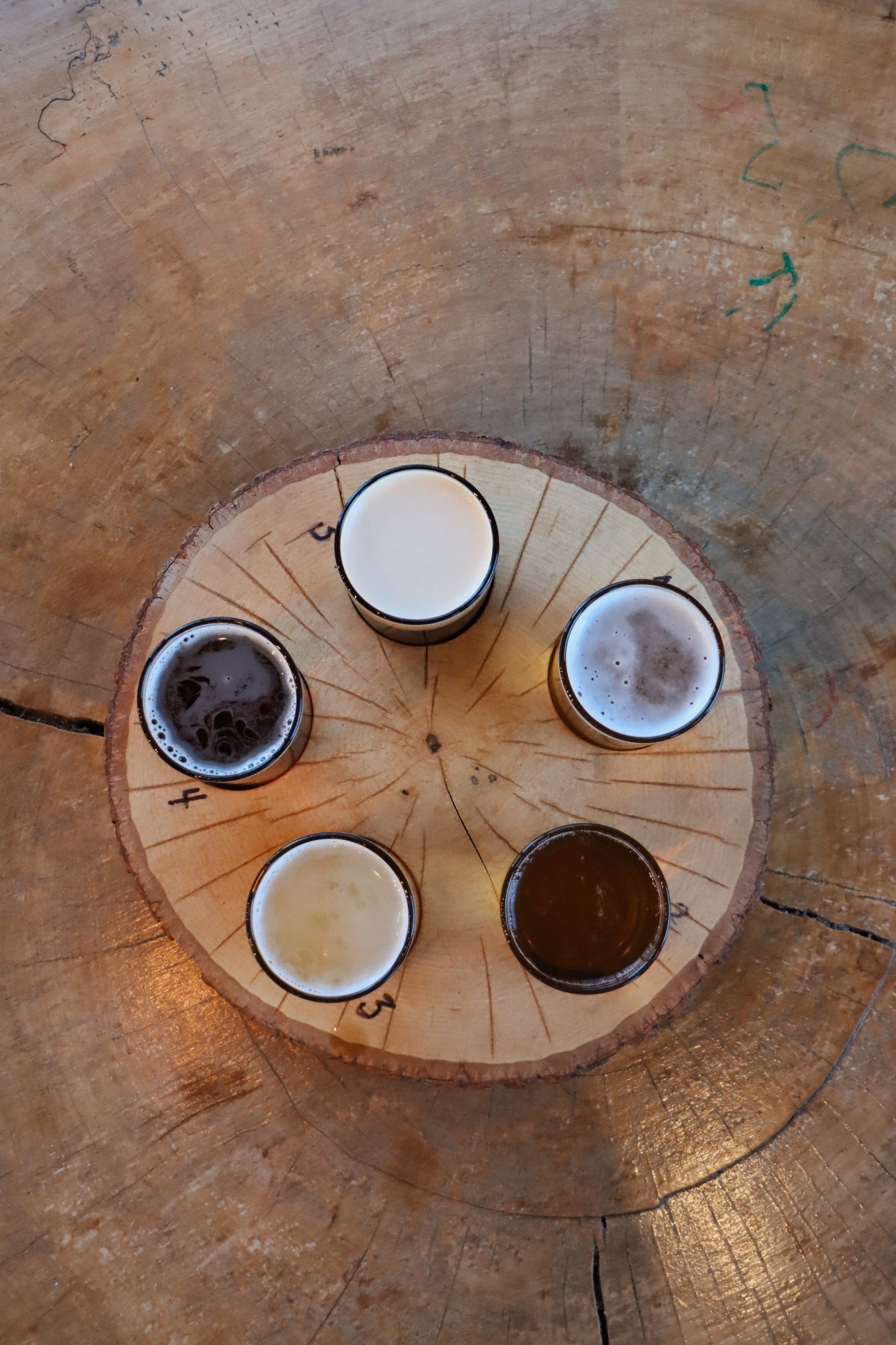 Four glasses of beer on a wooden coaster with a rustic background