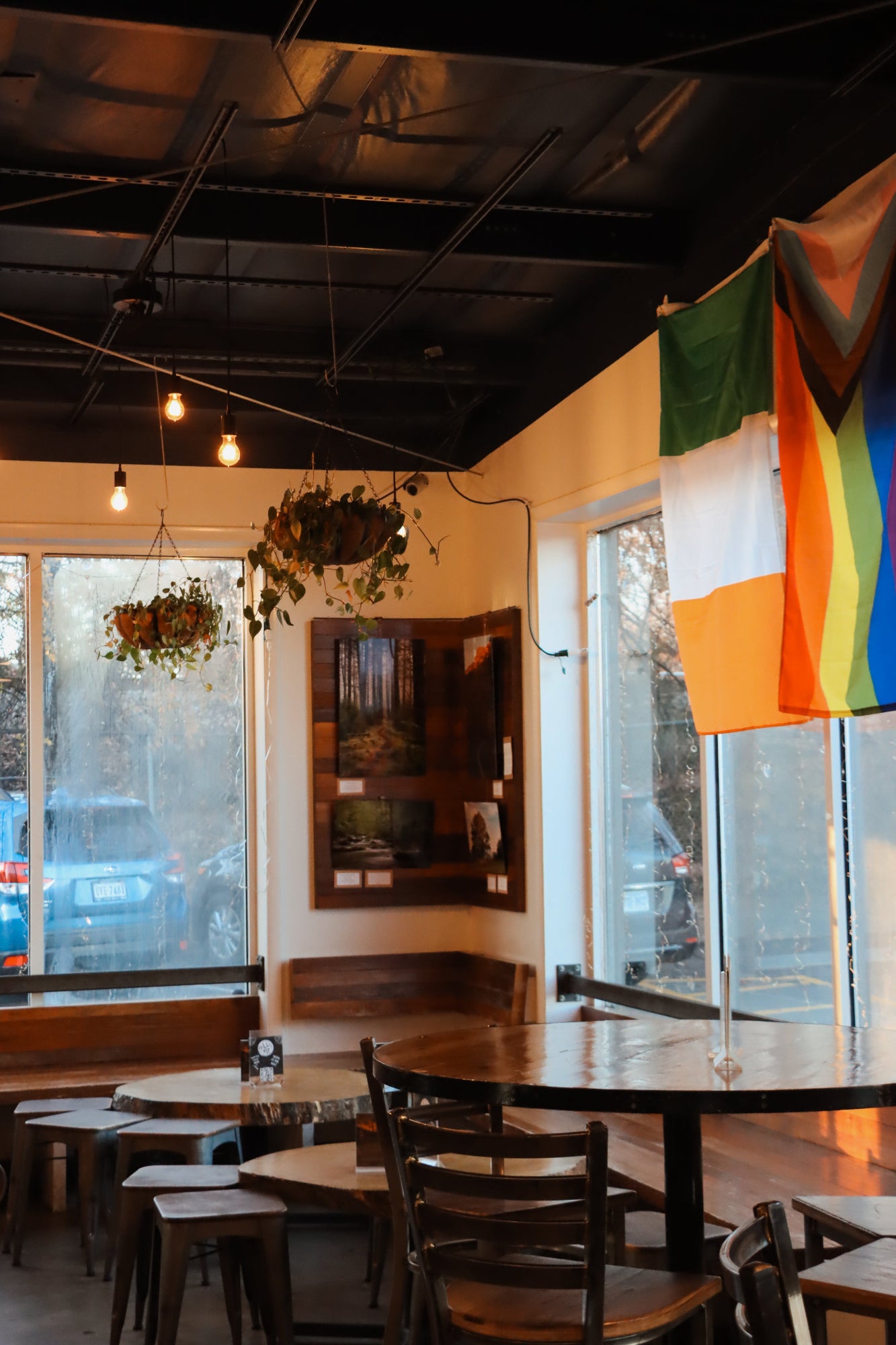 Dining area with tables, chairs, and a rainbow flag hanging on the wall.