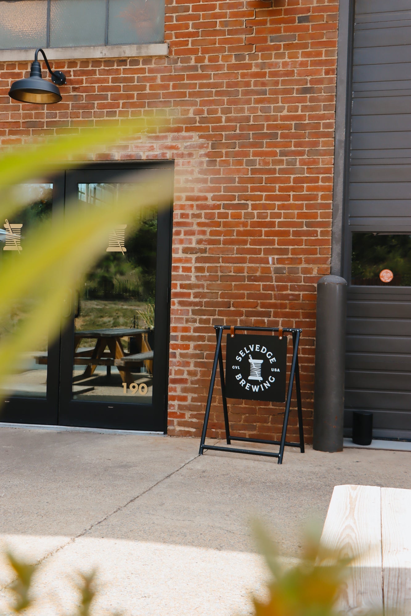 Brick building with a sign for 'Selvedge Brewing' outside.