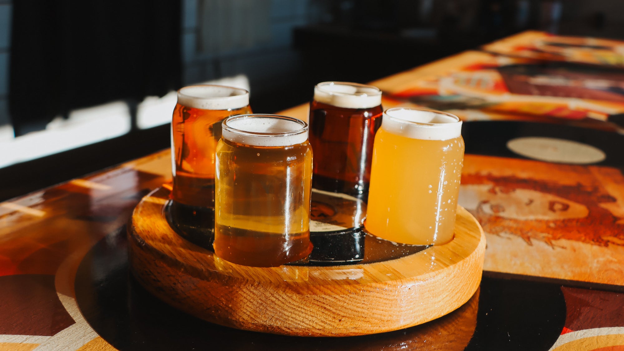 Four glasses of beer on a wooden tray with a blurred background